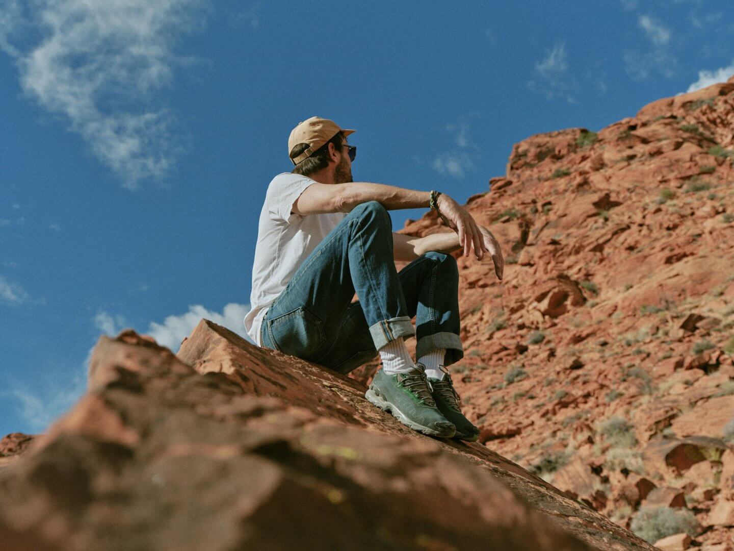 Man sitting on a rock near Miraluna, a luxury apartment rental in a desert landscape in Las Vegas.